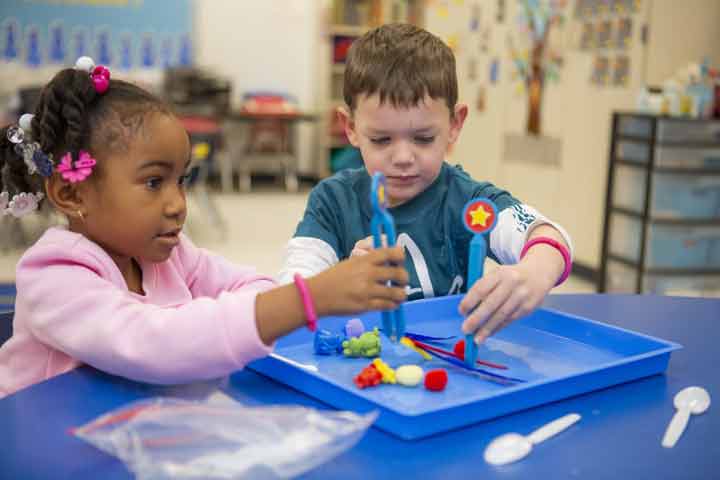 Two children using tweasers to pick up items