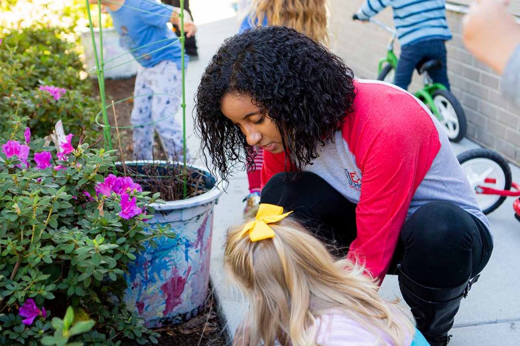 child and teacher working in garden together