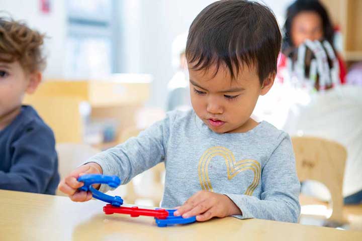 A boy trying to build with connecting sticks.