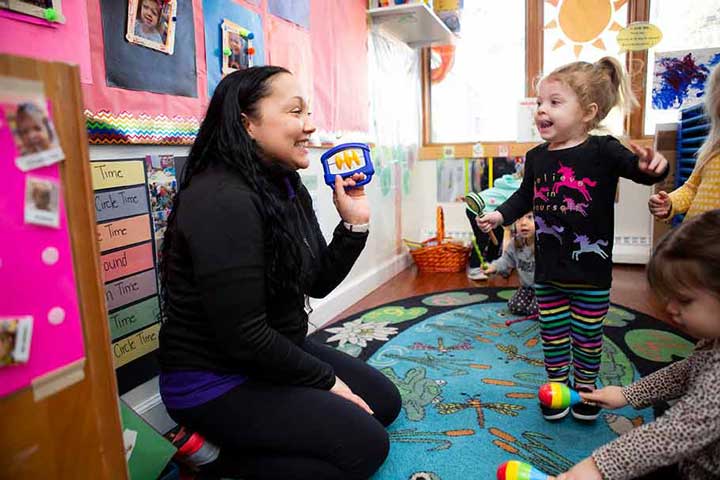 Teacher holding musical shaker with little girl dancing.