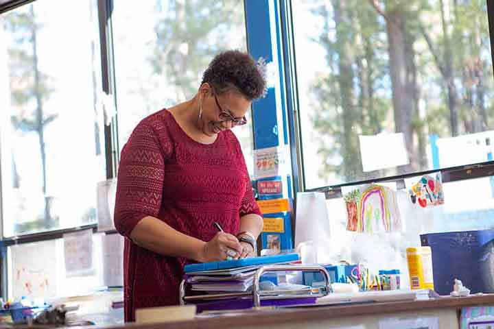 A teacher making a note in her notebook.