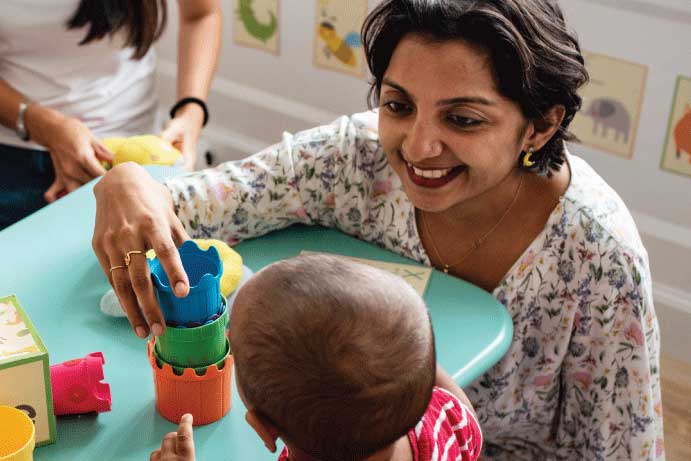 Woman and boy in preschool classroom play with stacking blocks